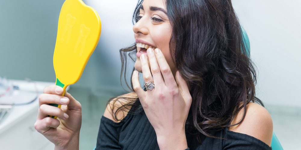 Lady Checking Teeth in yellow mirror