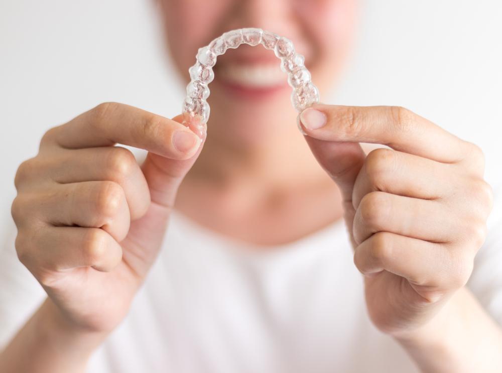 A,Smiling,Woman,Holding,Invisalign,Or,Invisible,Braces,,Orthodontic,Equipment invisalign braces