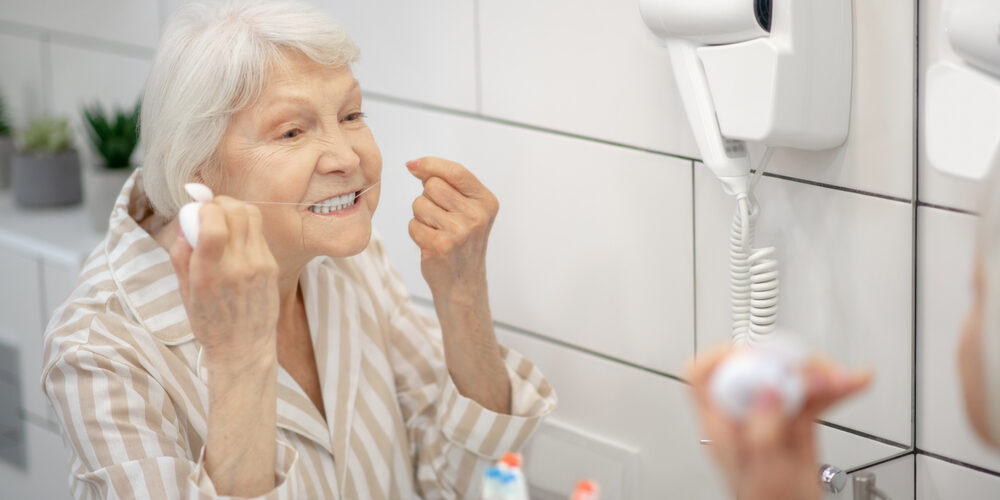 Cleaning Teeth. Gray haired Woman Cleaning Her Teeth And Using Floss
